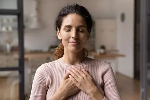 mulher feliz gratidão coração mão no peito