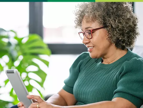 mulher de óculos sorrindo para tablet